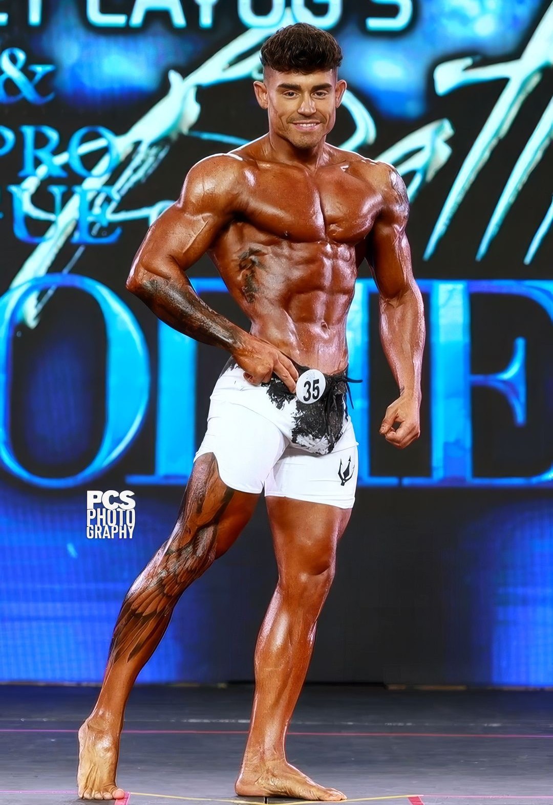 Lázaro Ruiz en el escenario de Men's Physique — competidor #35, fotografía profesional por PCS Photography